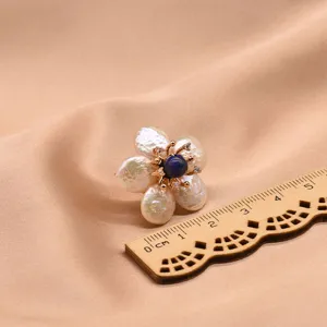 Detailaufnahme von Barockperlen Blumenohrringen mit blauem Mittelstein und Holzmabstab.