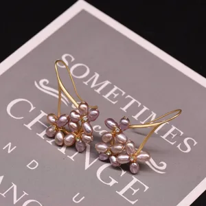Detailed close-up of handmade freshwater purple pearl flower earrings with gold hooks.