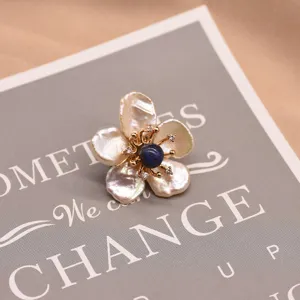 Elegant baroque pearl flower brooch with blue center stone and gold plated details.