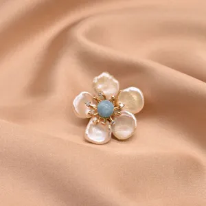 Close-up detail shot of an elegant baroque pearl flower brooch with blue center.