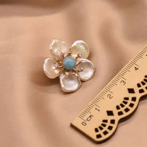 Detailed shot of baroque pearl flower brooch showcasing blue bead and sparkling crystal accents.