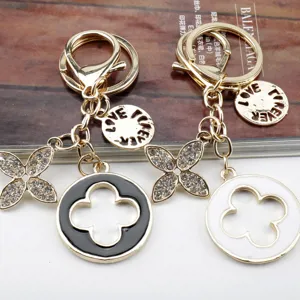 Dettaglio di eleganti portachiavi con quadrifoglio in strass e ciondoli metallici lucidi.