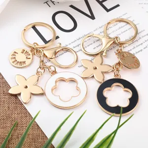 Set portachiavi in metallo con ciondoli fiori in smalto bianco e nero e targhetta amore.