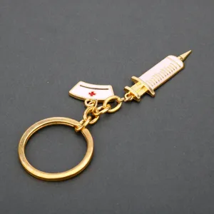 Nurse themed metal keychain with syringe and hat charms detailed view showing enamel craftsmanship.