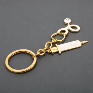 Medical theme metal keychain with stethoscope and syringe charms in gold and white enamel.