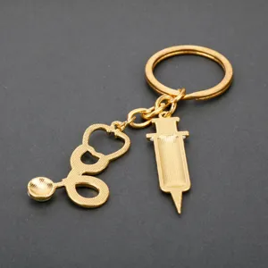 Gold medical theme keychain featuring stethoscope and syringe charm detail view.
