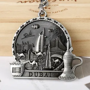 Close-up detail of Dubai metal keychain featuring iconic Burj Khalifa and camel relief design.