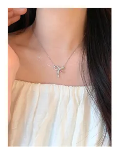 Primer plano del collar con lazo de plata y colgante brillante de piedra rosa.