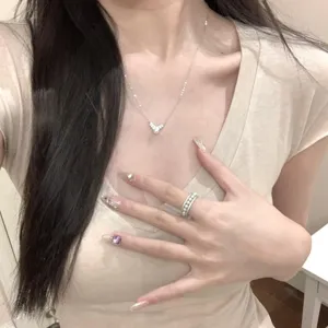 Primer plano de un delicado collar de plata S925 con perla y detalle de anillo en la mano.