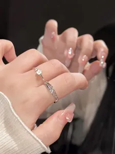 Detalle en primer plano de anillos de pareja de plata con una linda margarita y banda retorcida.