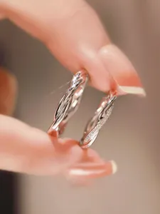 Close-up detail view of elegant silver intertwined couple rings featuring sparkling zircon stones.