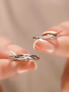 Close-up of intertwined sterling silver couple rings with sparkling pavé zircon stones.