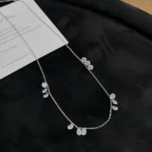 Détail en gros plan du collier pendentif goutte d'eau scintillant sur fond noir élégant.