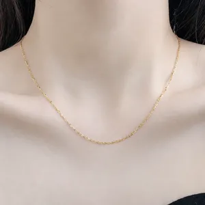 Detailaufnahme einer zarten, goldfarbenen O-Kette, die elegant am Hals getragen wird.