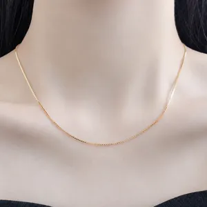 Nahaufnahme einer zarten goldfarbenen Box-Kette, die elegant und stilvoll am Hals getragen wird.