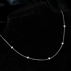 Detalle de collar de trébol de cuatro hojas de plata con cadena fina y circonitas brillantes.
