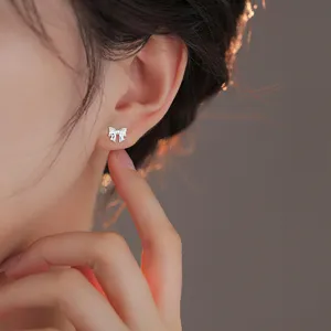Gros plan détaillé d'une boucle d'oreille clou nœud en argent sterling portée au lobe.