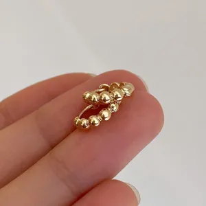 Close-up detail of gold plated beaded small hoop earrings, minimalist style everyday wear.