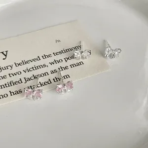 Gros plan détail de boucles d'oreilles nœud en argent avec cristaux roses et transparents.