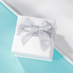 Scatola regalo per gioielli bianca con elegante fiocco argento, ideale per anelli e accessori.
