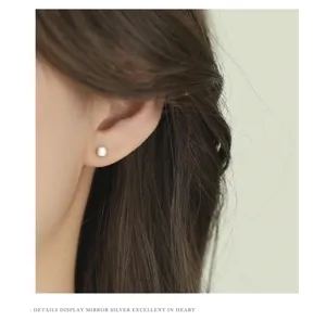 Primer plano detallado de pendientes minimalistas mate cepillados llevados en la oreja.