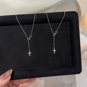 Detailed close-up view of silver and gold infinity cross pendant necklaces on black velvet tray.