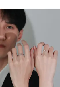 Primer plano detallado de anillos de pareja de plata con margarita y diseño trenzado.