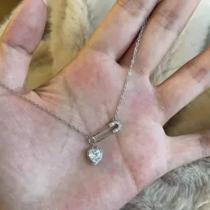 Detail shot of a s925 silver safety pin necklace with a sparkling heart zircon pendant.