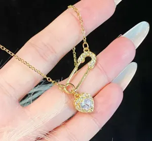 Close-up of S925 silver safety pin necklace featuring a sparkling zirconia heart pendant.