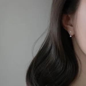 Primer plano detallado de pendientes colgantes de plata S925 minimalistas con pequeños diamantes.