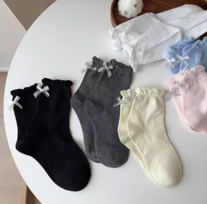 Detailaufnahme süßer Baumwollsocken mit feiner Schleifendekoration und zarten Rüschenbündchen.