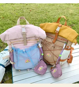 Outdoor detail view of canvas roll-top student backpacks with mesh pockets and pouch.