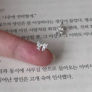 Gros plan détail des mini boucles d'oreilles clous nœud en argent sterling sur un livre.