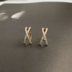 Primer plano detallado de pendientes de botón de plata S925 cruzados con circonitas brillantes.