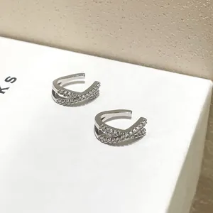 Pendiente de oreja cruzado de plata con circonitas, sin perforación, estilo elegante.