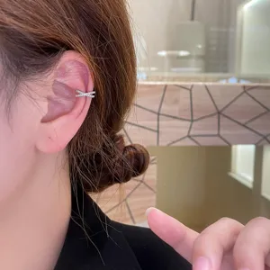 Primer plano de detalle de un hermoso pendiente de oreja cruzado brillante en el cartílago.