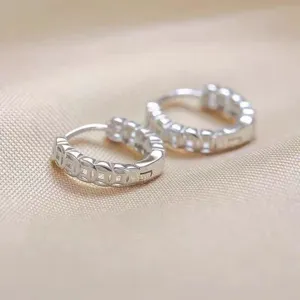Detalle de cerca de pendientes de aro de plata S999 con moneda de cobre y textura de lujo.