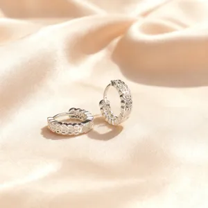 Detalle de primeros planos de pendientes de aro de plata huecos, diseño de joyería elegante.