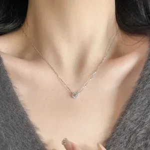 Gros plan sur un délicat collier en argent doté d'un pendentif double anneau entrelacé.