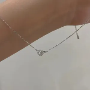 Gros plan détaillé du collier en argent avec deux anneaux entrelacés et des zircons scintillants.