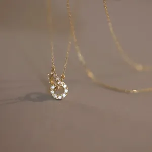 Délicat collier pendentif double anneau en argent plaqué or 18K détail scintillant.