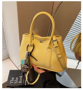 Nahaufnahmen der stilvollen gelben Tasche, die Ledertextur und feine Hardware betonen.