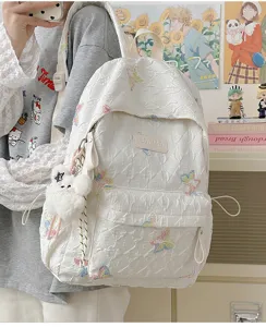 Nahaufnahme des weißen gesteppten Rucksacks mit bunter Schmetterlingsstickerei und Anhängern.