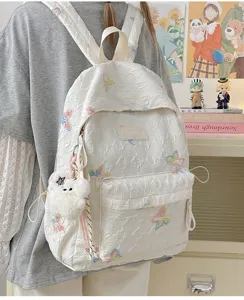 Detailansicht des weißen gesteppten Rucksacks mit Schmetterlingsstickerei und Anhänger für Schule.