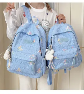 Süßer blauer gesteppter Schulrucksack mit Schmetterlingsstickerei und Plüschbäranhänger.