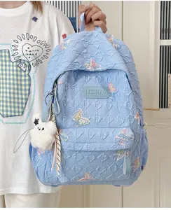 Detailansicht des gesteppten Rucksacks mit bunten Schmetterlingsstickereien und Plüschanhänger.