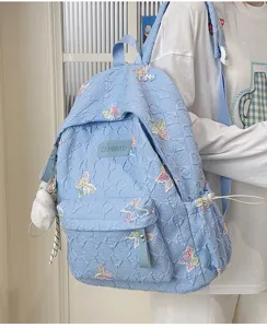 Detailansicht des niedlichen blauen Rucksacks mit Schmetterlingsstickerei und Steppdesign.