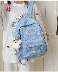 Hellblauer gesteppter Rucksack mit süßen gestickten Schmetterlingen und Plüschbär-Anhänger.