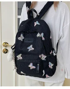 Detailansicht des schwarzen Rucksacks mit bunten Schmetterlingsstickereien und Plüsch.