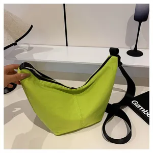 Primer plano del bolso de hombro cruzado verde neón, con correa negra y gran capacidad útil.